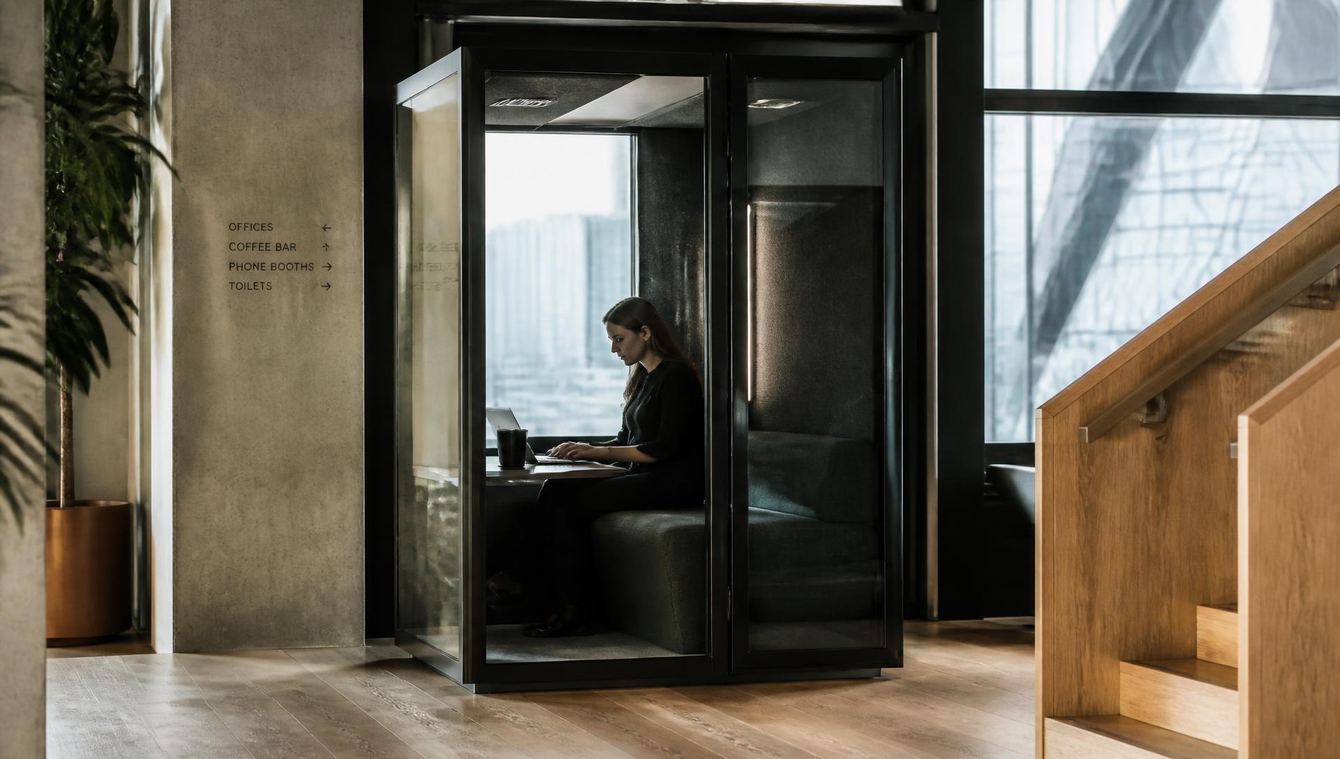 A person working inside a MOVNI acoustic booth in a premium office